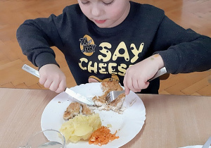 Kubuś używa widelca i noża podczas posiłku.